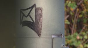 Briefumschlag-Graffito auf einem Laternenpfahl